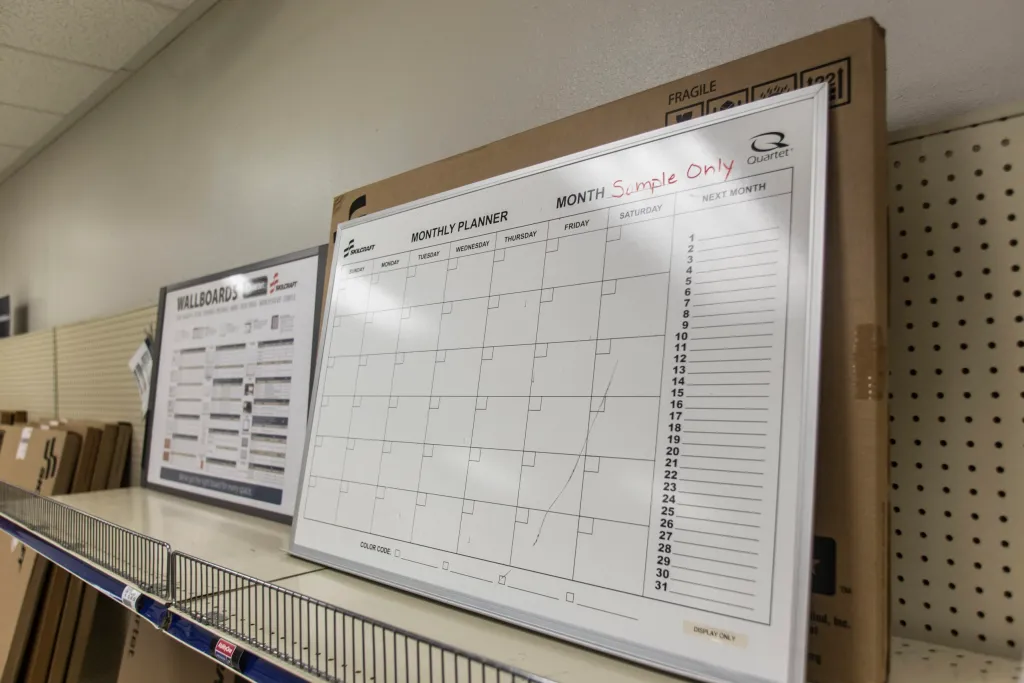A large wall board with a calendar outline on it sitting on a shelf in a store